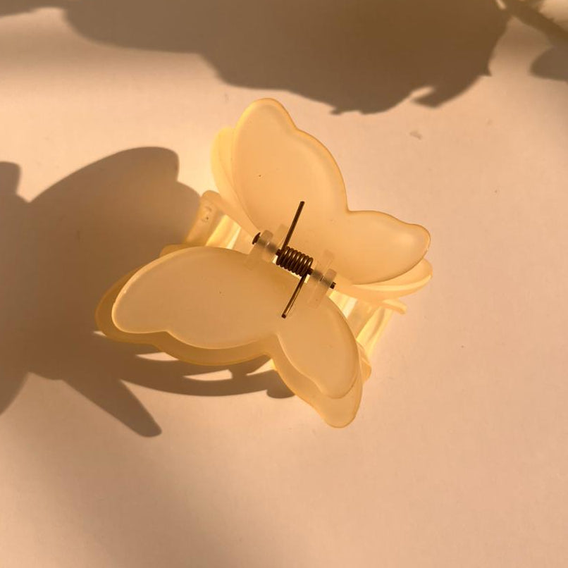 Butterfly-shaped hair clip on a light surface with shadows