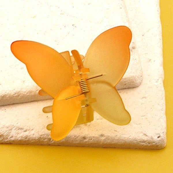Yellow butterfly hair clip on a textured surface with a yellow background
