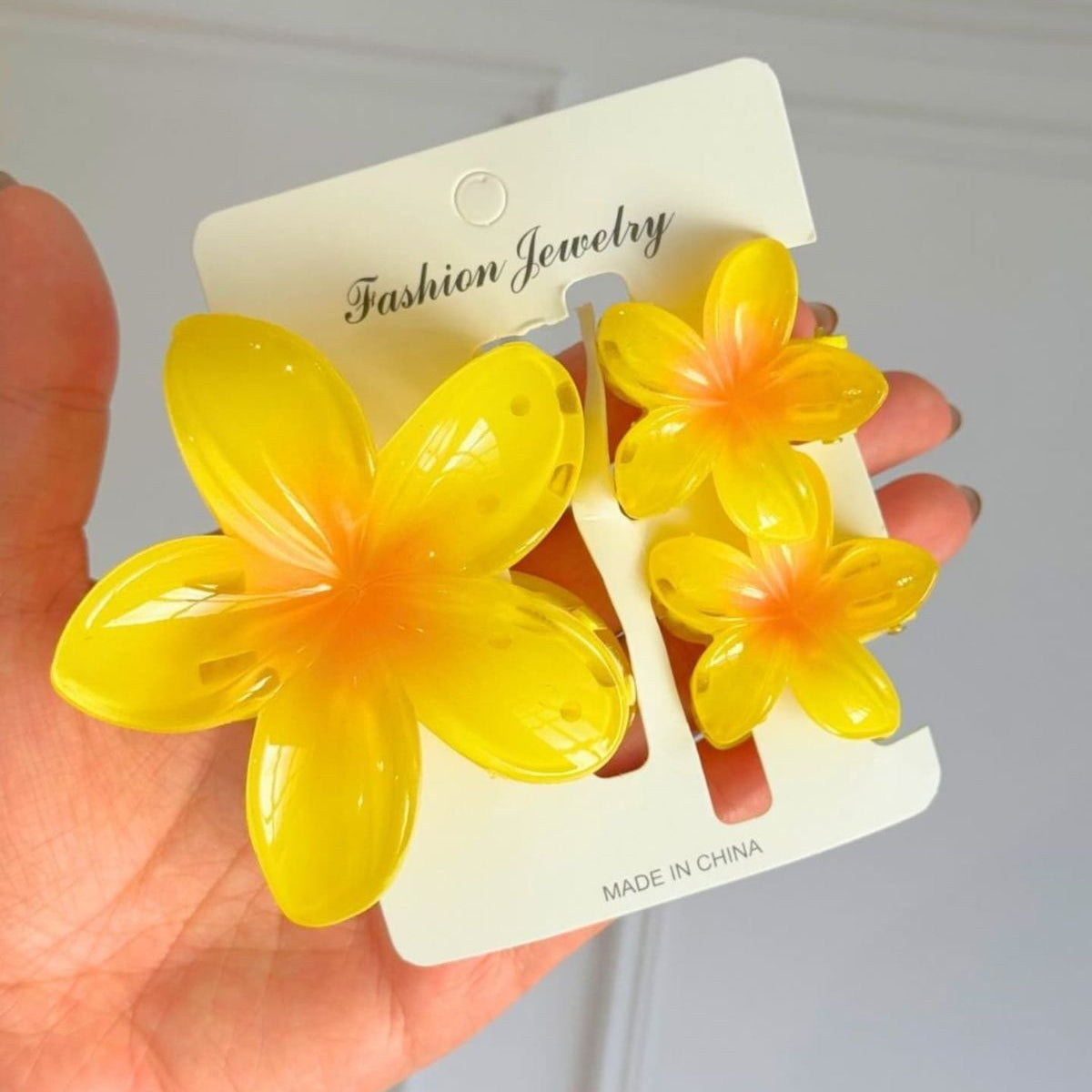 Yellow flower-shaped hair clips on a 'Fashion Jewelry' card held by a hand.