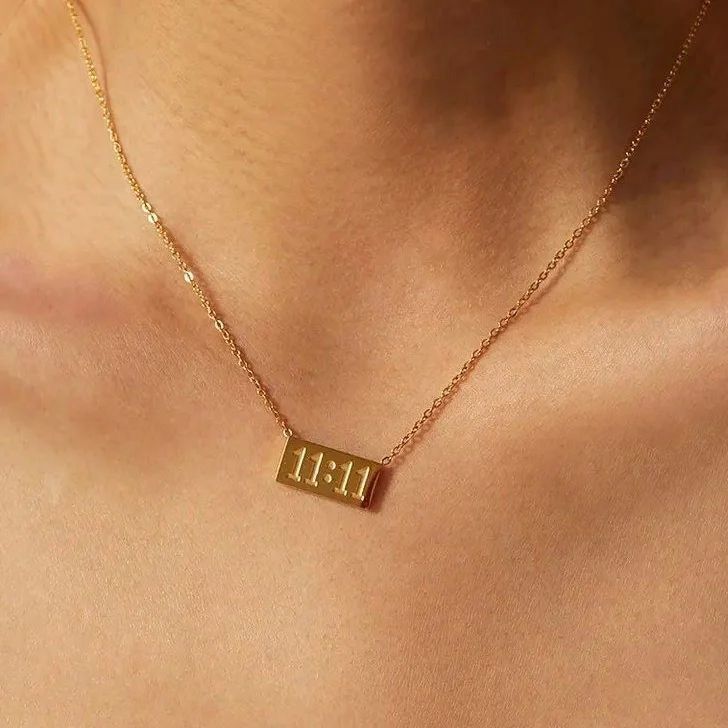 Gold necklace with a rectangular pendant on a person's neck