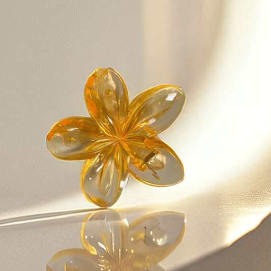Clear yellow flower-shaped object on a reflective surface with a blurred background