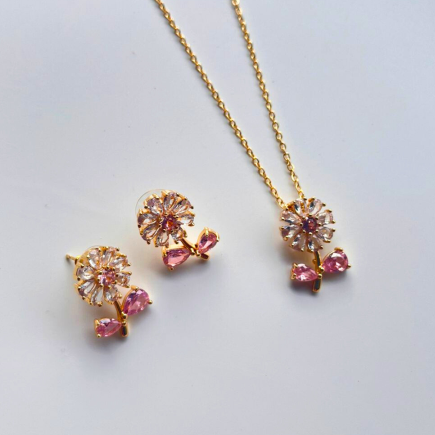 Gold jewelry set with pink gemstones on a light gray background