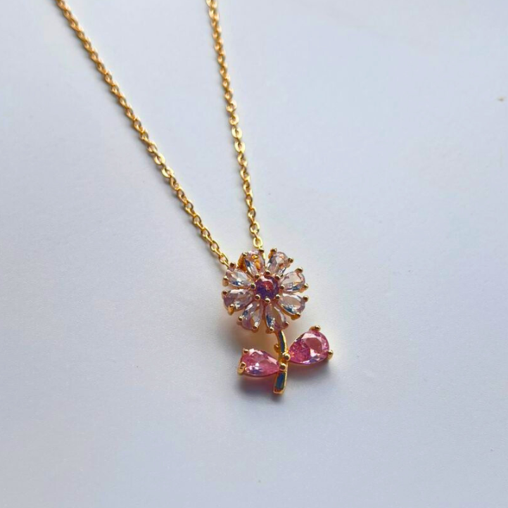 Gold necklace with a pink gemstone pendant on a light gray background