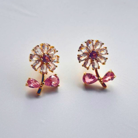 Pair of flower-shaped earrings with pink gemstones on a light gray background