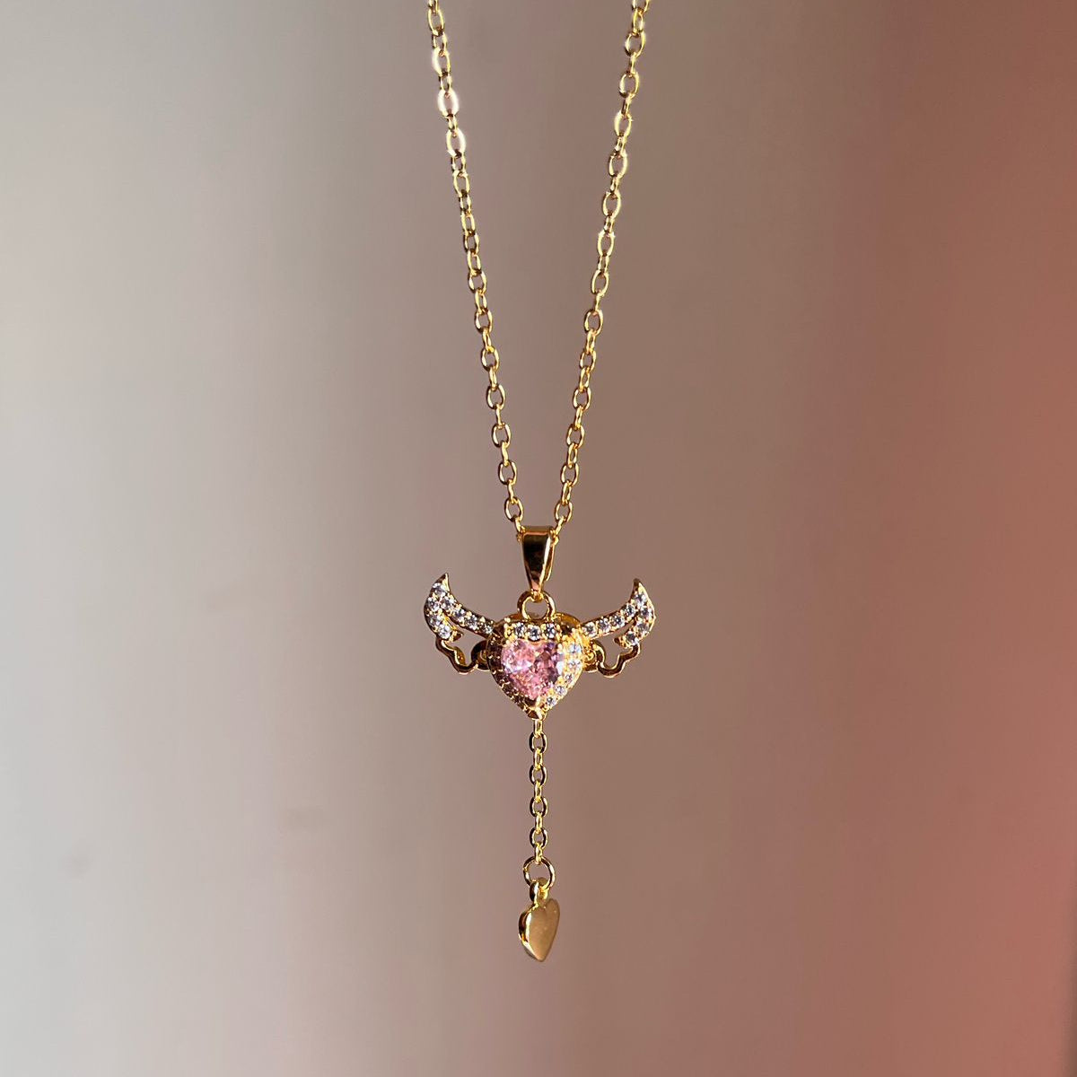 Gold necklace with a heart-shaped pendant on a gradient background
