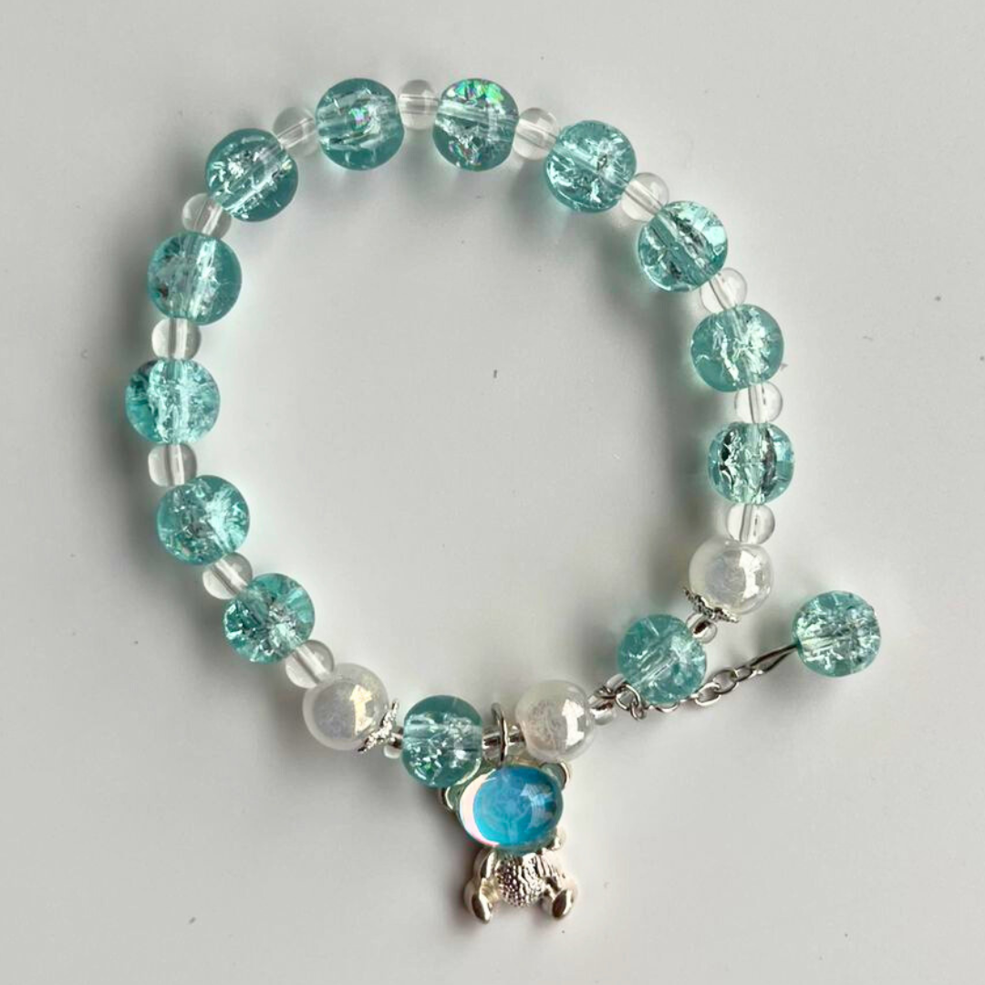 Beaded bracelet with turquoise and clear beads on a light gray background
