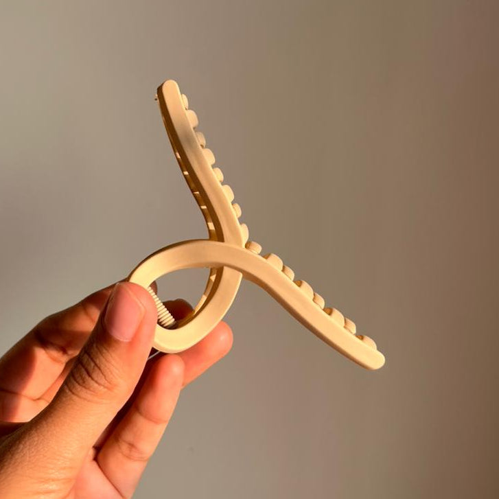 Hand holding a beige clip against a plain background