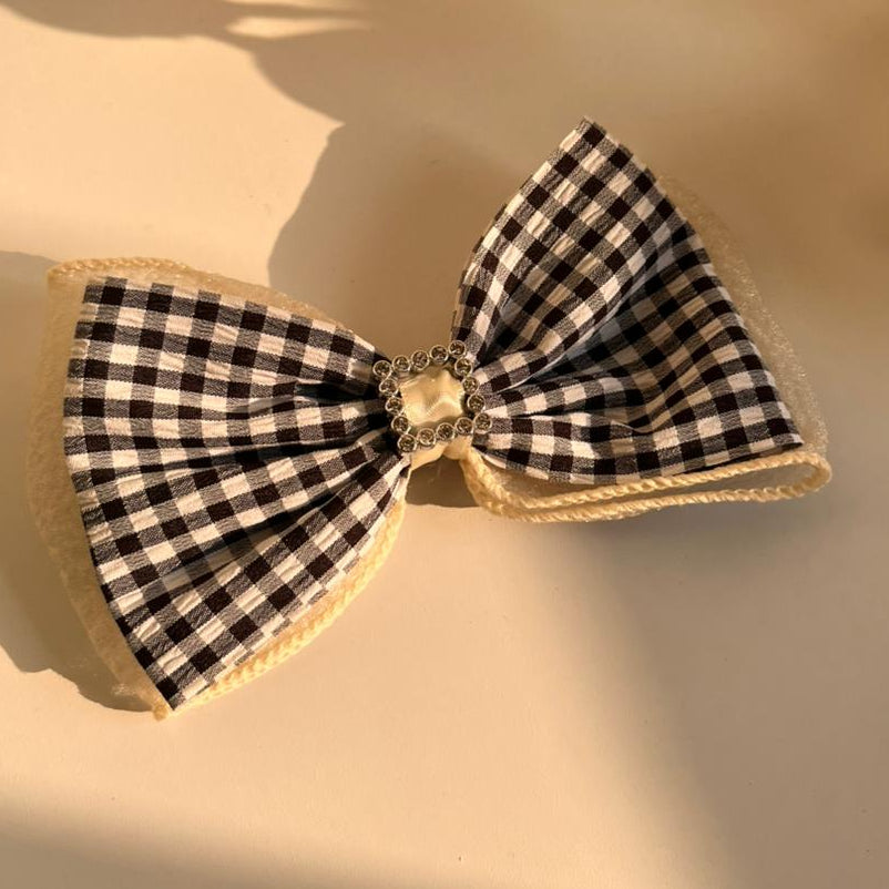 Black and white checkered bow with gold trim on a light surface.