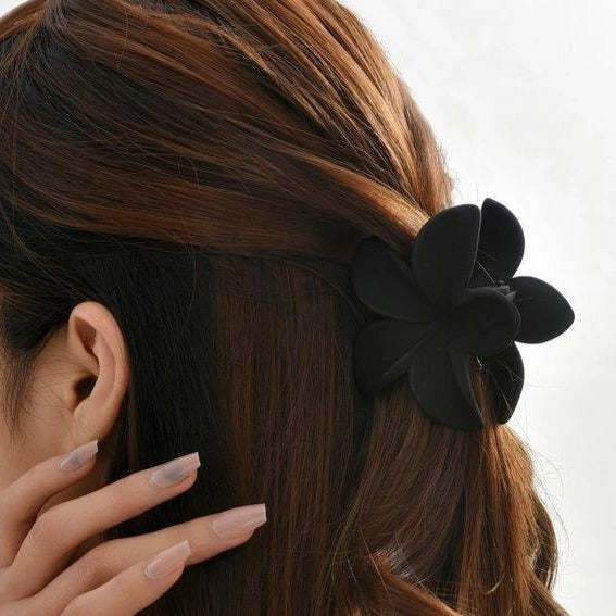 Black hair clip worn in a person's hair with a neutral background