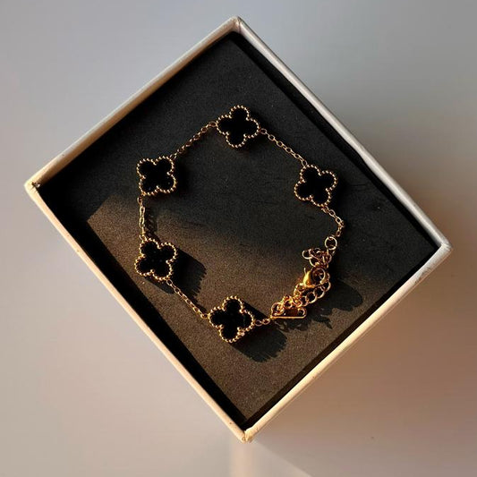 Bracelet with clover designs in a box on a gradient background