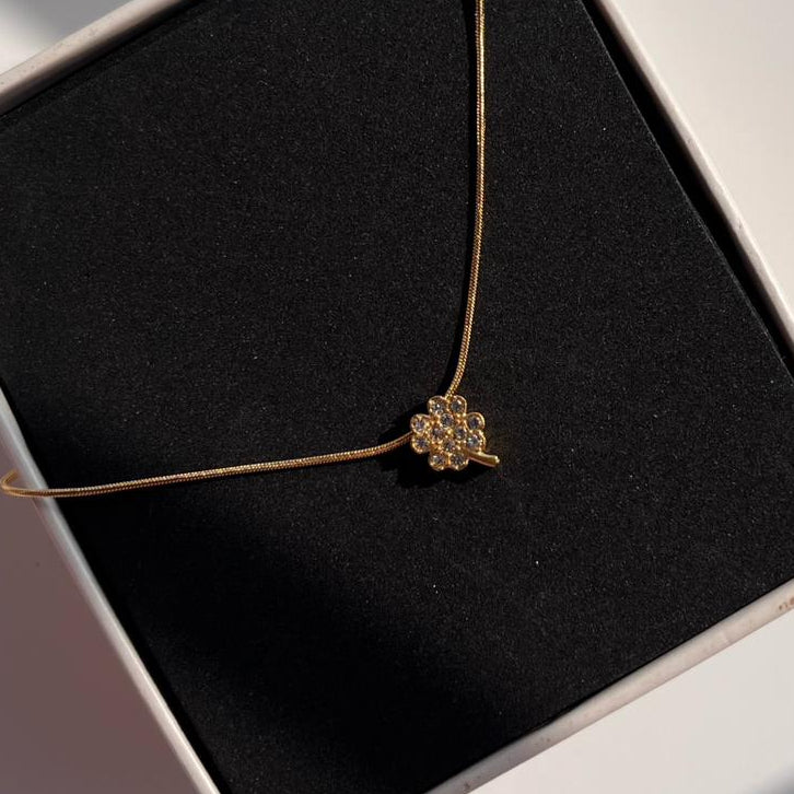 Gold necklace with a pendant in a black jewelry box on a light gray background