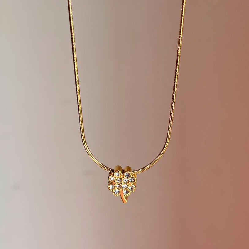 Gold necklace with a flower-shaped pendant on a gradient background
