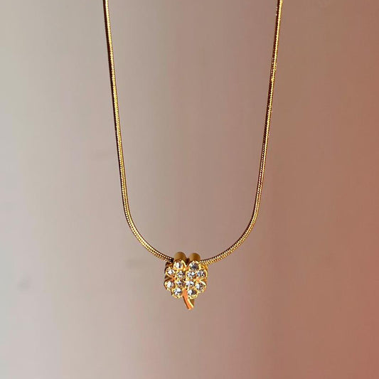 Gold necklace with a flower-shaped pendant on a gradient background