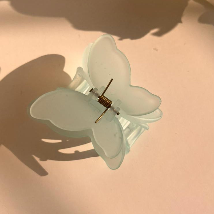 Butterfly-shaped hair clip on a pink surface with shadows