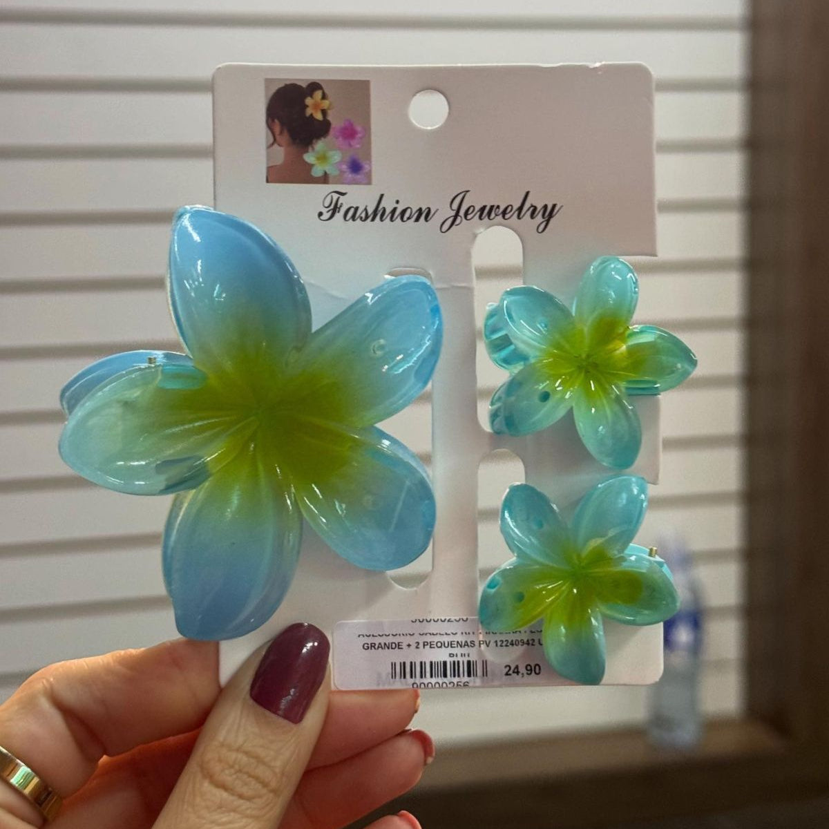 Blue and green flower-shaped hair accessories on a card held by a hand.
