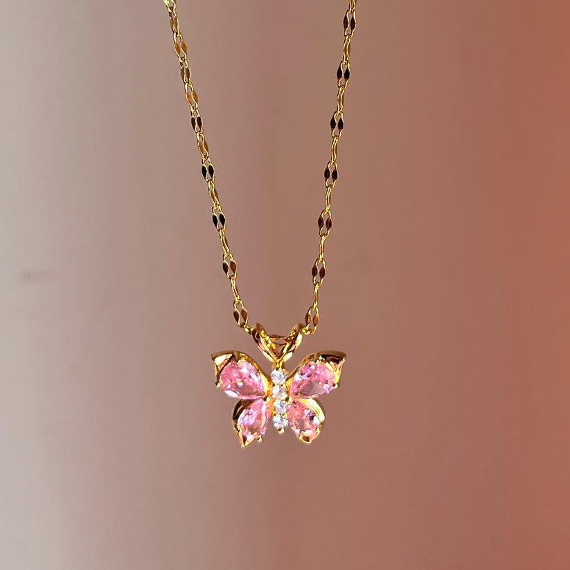Gold necklace with a pink butterfly pendant on a gradient background