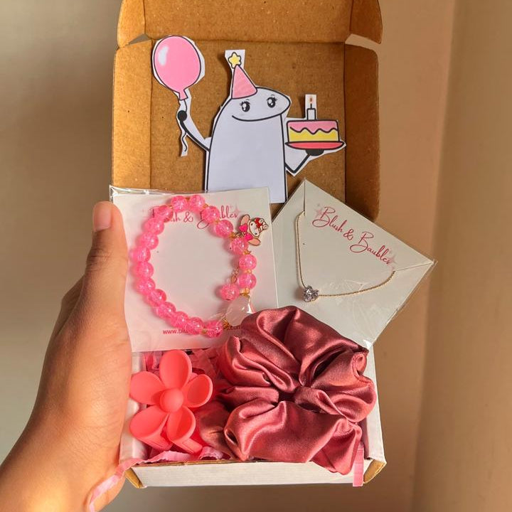 Box of pink hair accessories including bracelets, a necklace, and scrunchies held by a hand.