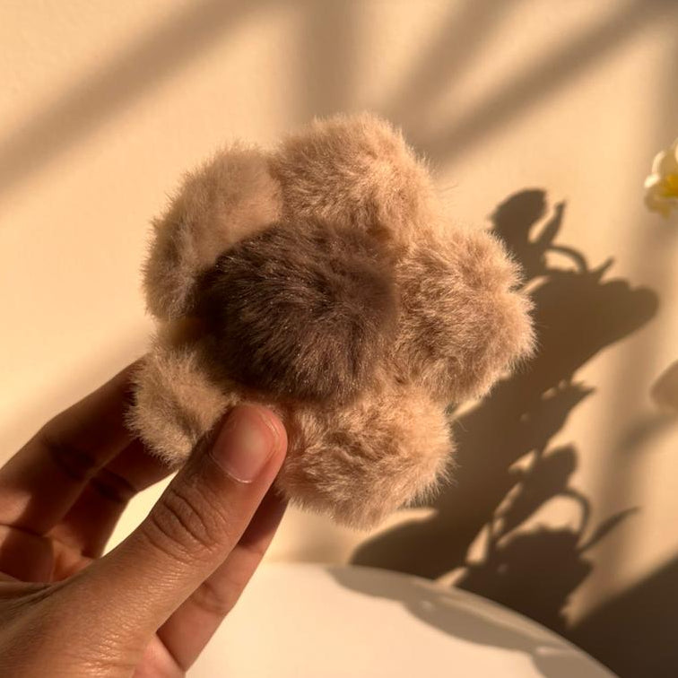 Hand holding a small hair clip with a soft light background