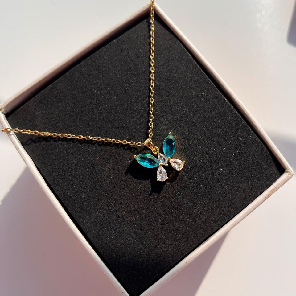 Necklace with a butterfly pendant featuring green and clear stones in a box