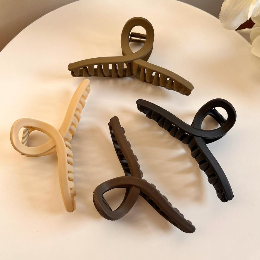 Set of four hair clips in different colors on a white plate with a floral background.