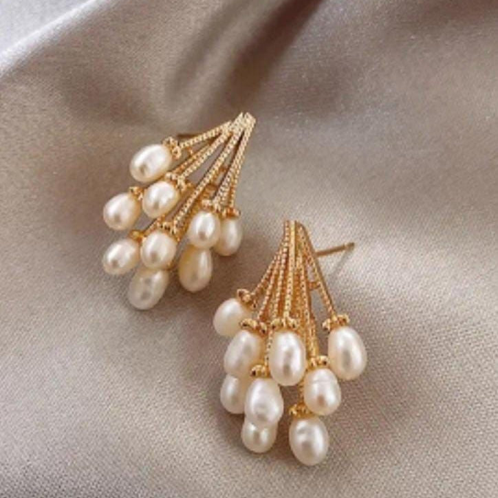 Pearl earrings with gold accents on a beige fabric background