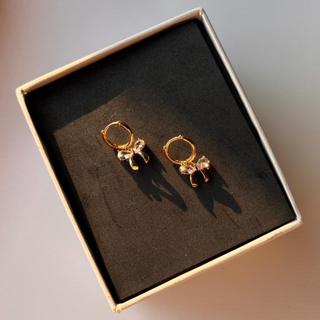 Gold earrings in a box on a light background
