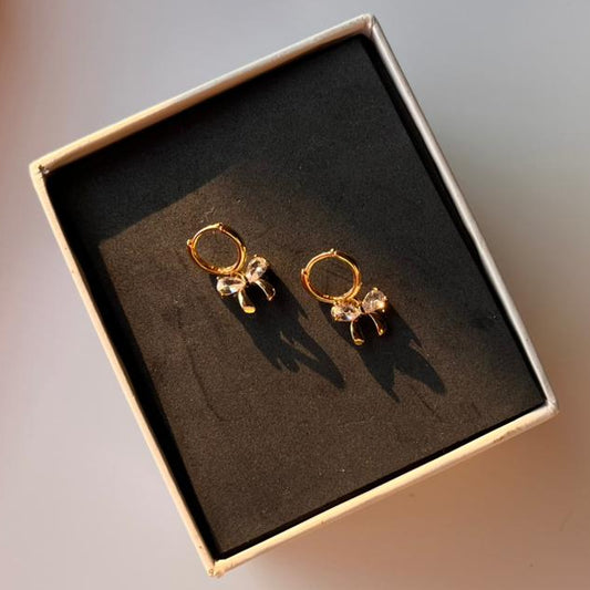 Gold earrings in a box on a light background