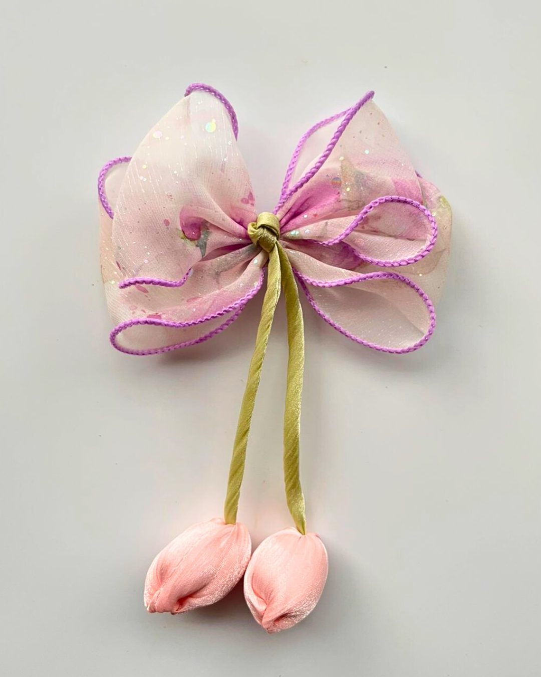 Pink bow with green stem and pink buds on a light gray background