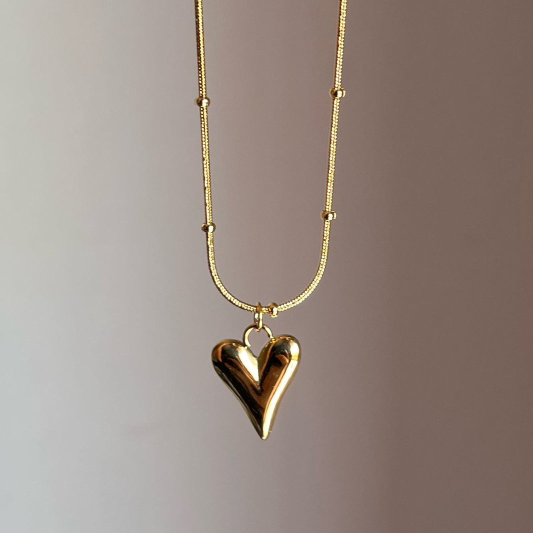 Gold heart-shaped pendant necklace on a gradient background