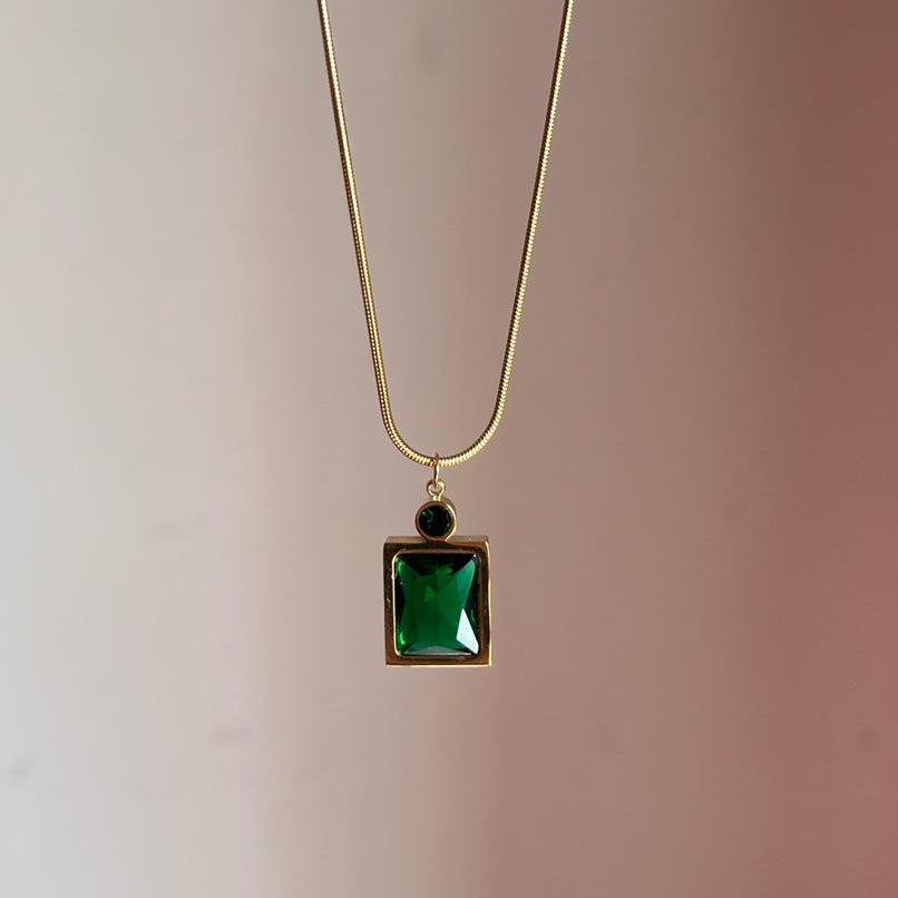 Necklace with a green square pendant on a plain background