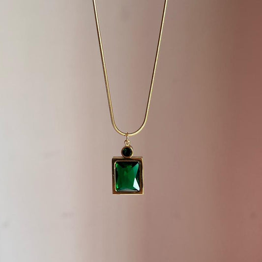 Necklace with a green square pendant on a plain background