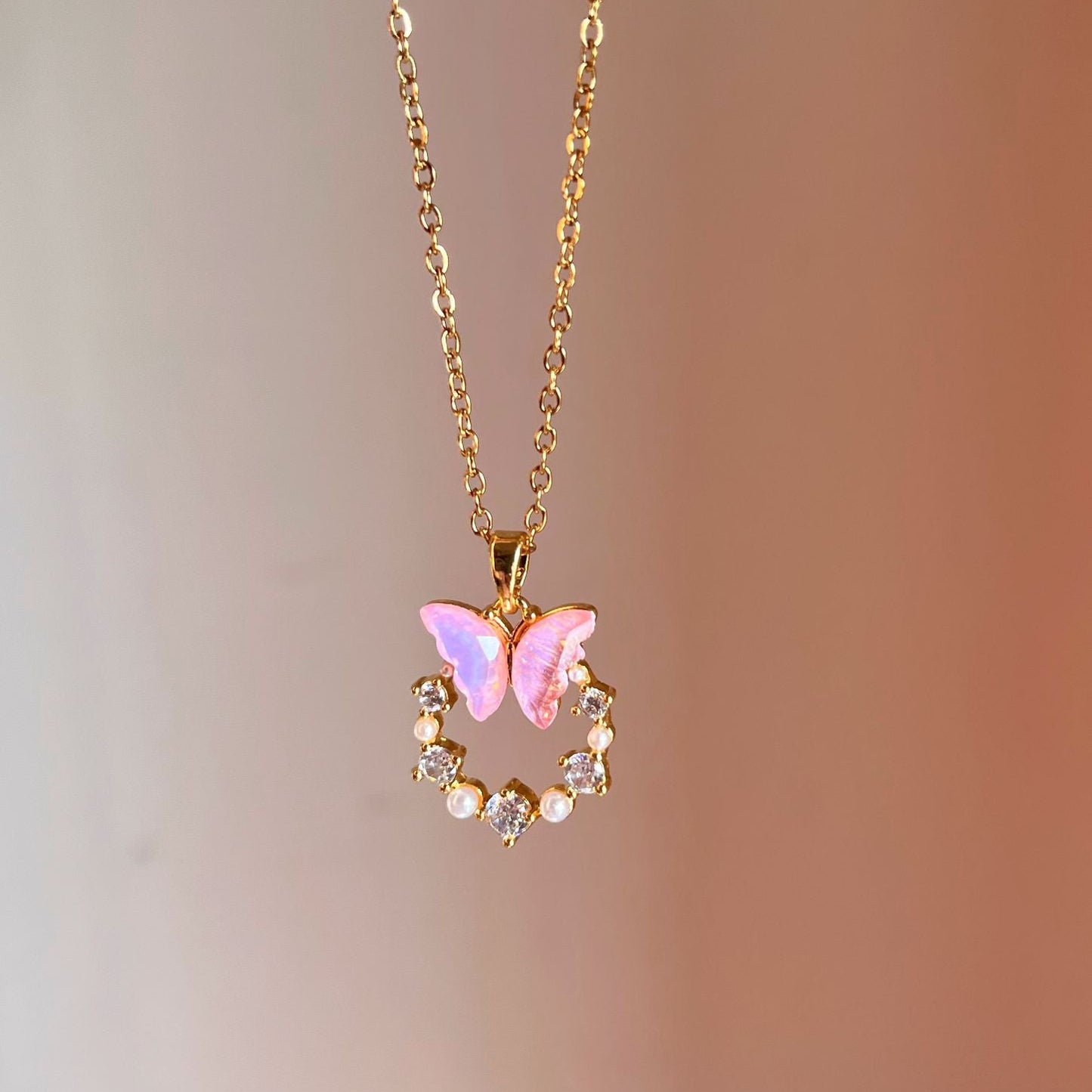 Necklace with a pink butterfly pendant on a blurred background