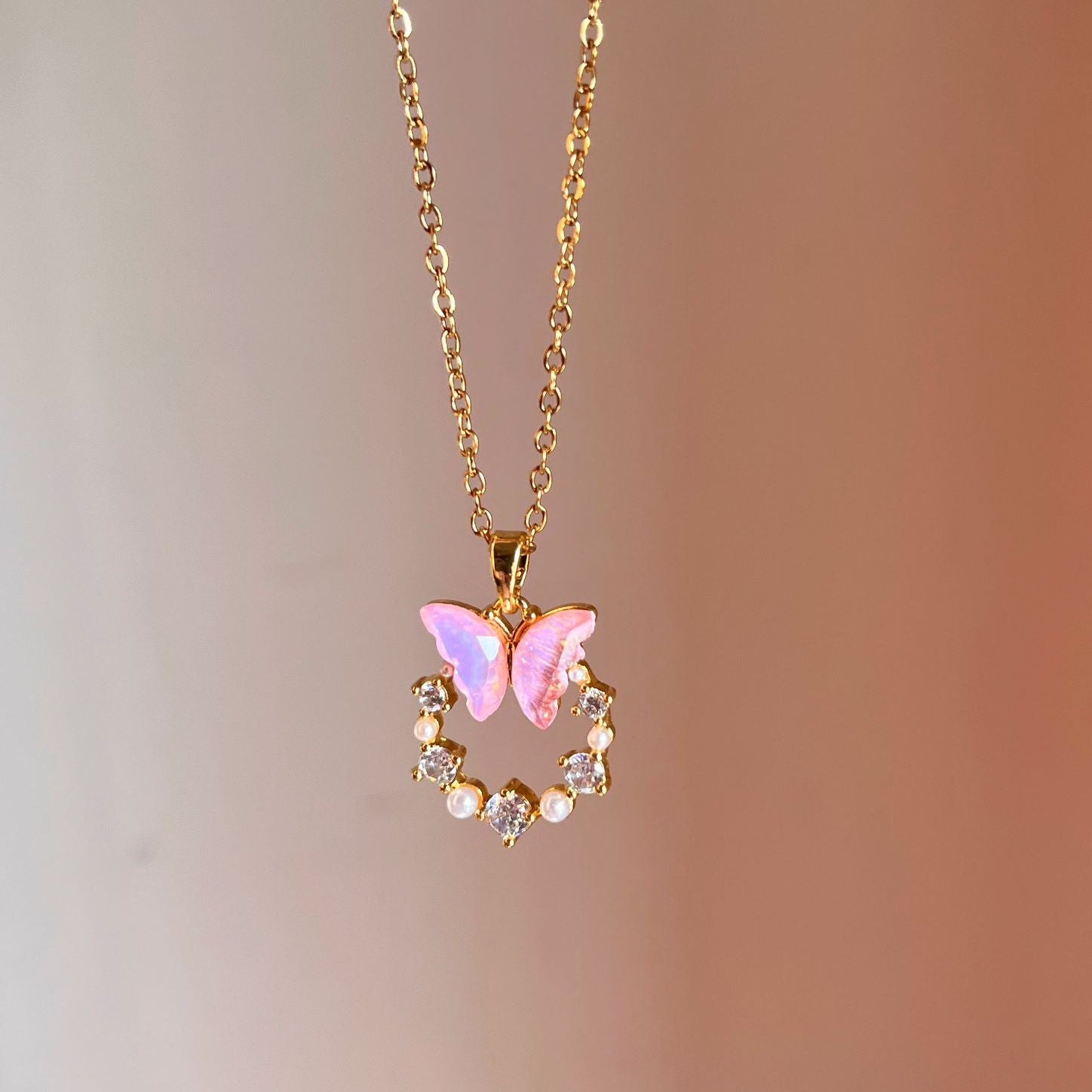 Necklace with a pink butterfly pendant on a blurred background