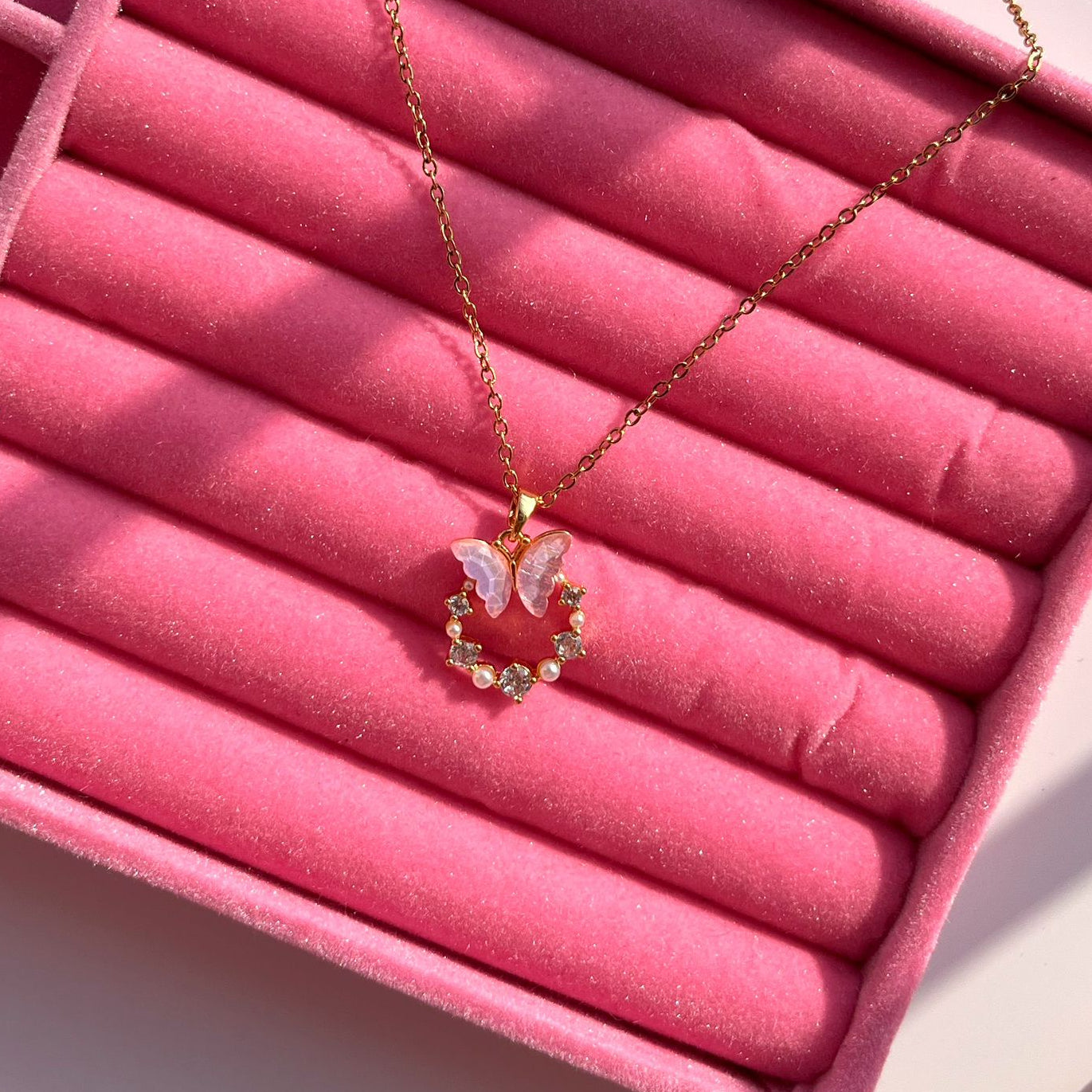 Necklace with a butterfly pendant on a pink velvet surface