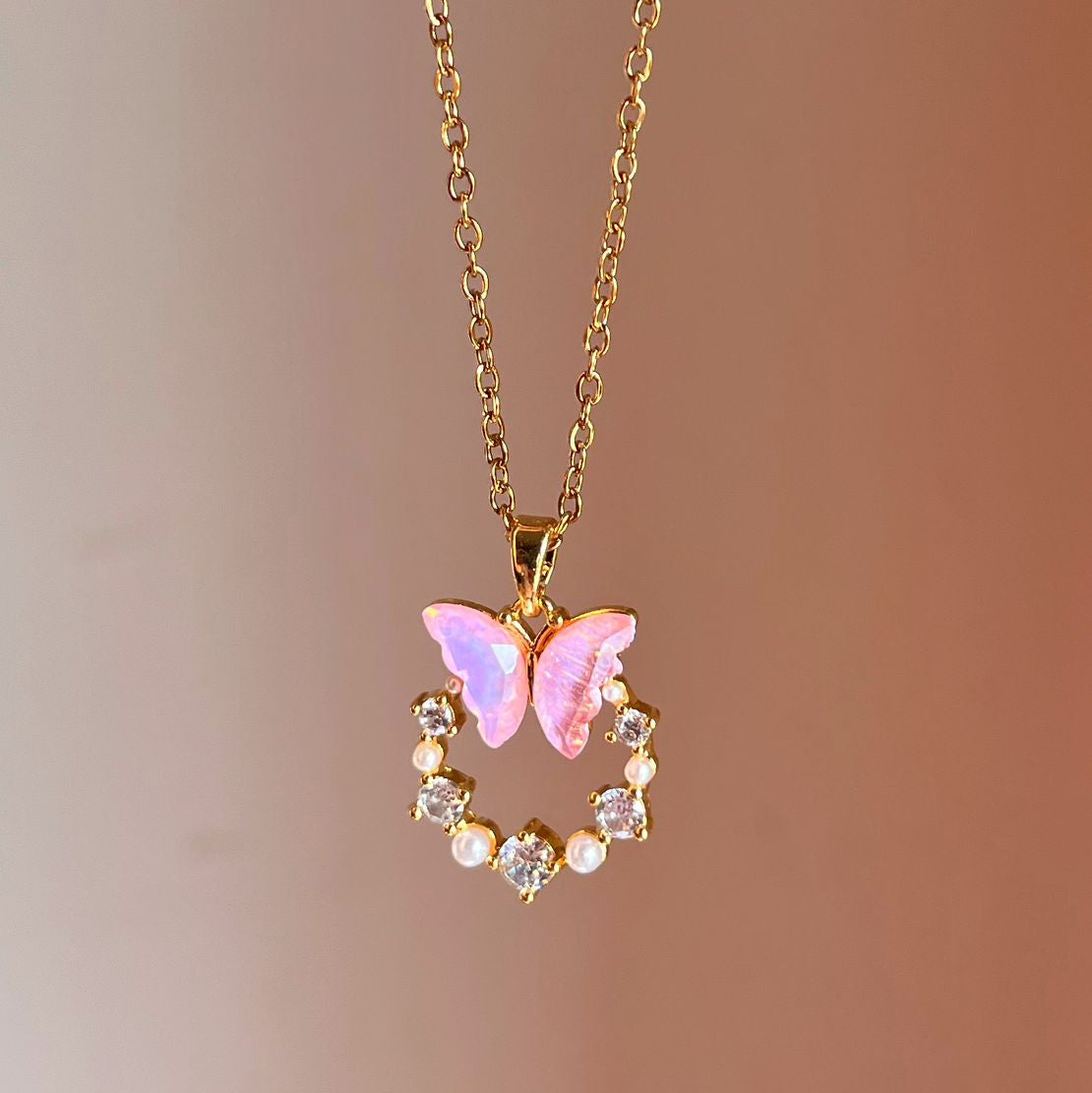 Necklace with a pink butterfly pendant on a blurred background