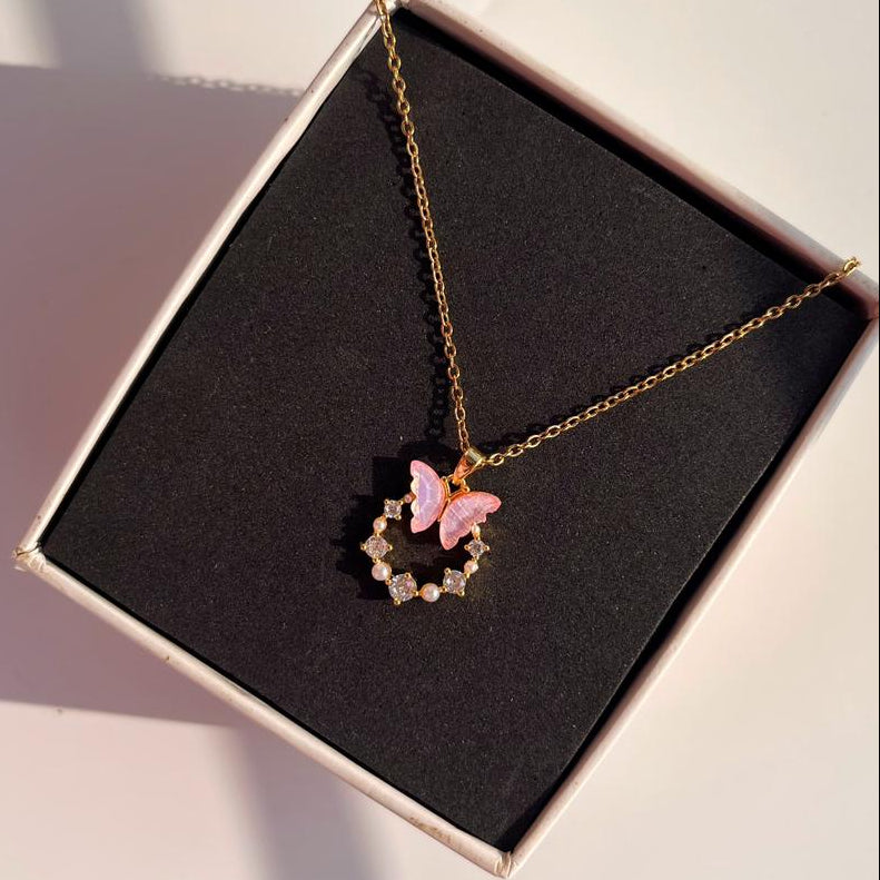 Necklace with a pink butterfly pendant on a black box