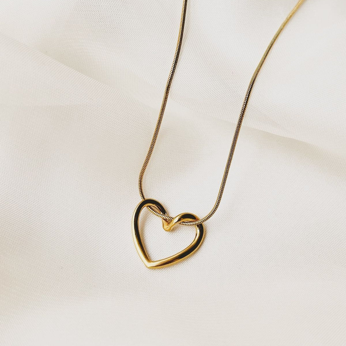 Gold heart-shaped necklace on a light fabric background