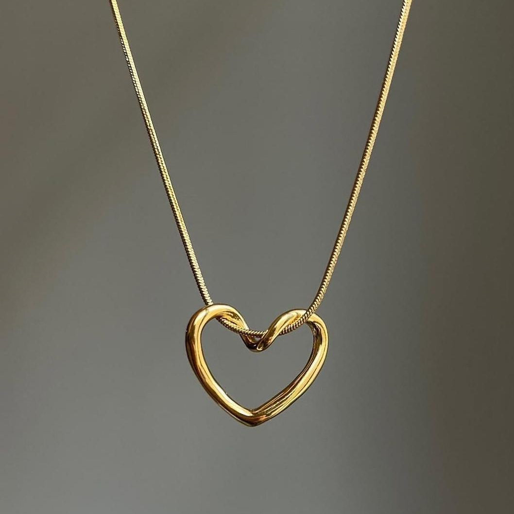 Gold heart-shaped necklace on a gray background
