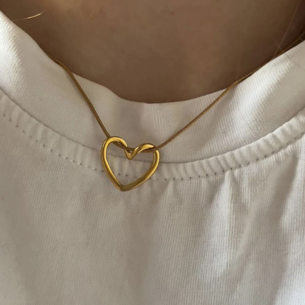 Gold heart-shaped necklace on a person wearing a white shirt