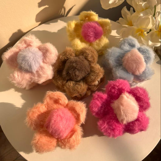 Colorful flower-shaped hair clips on a round surface with flowers in the background