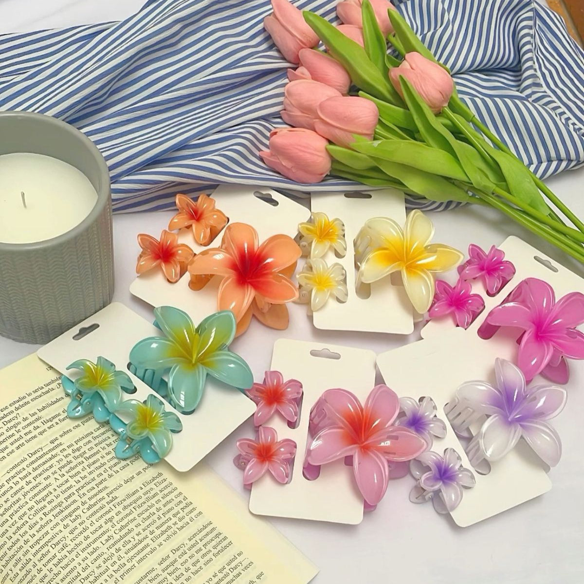 Colorful flower-shaped hair clips on cards with a candle and tulips in the background.