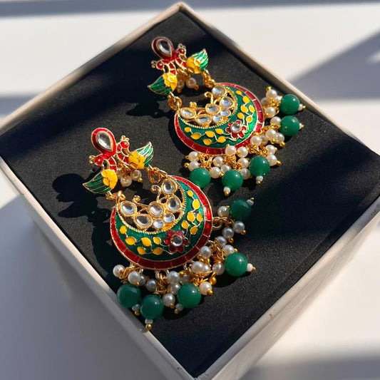 Colorful earrings with green stones on a black box