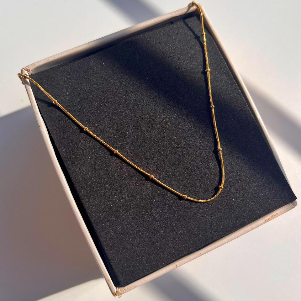Necklace on a black box with a white background