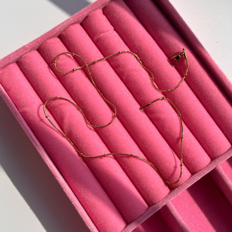 Gold necklace on pink velvet in a jewelry box