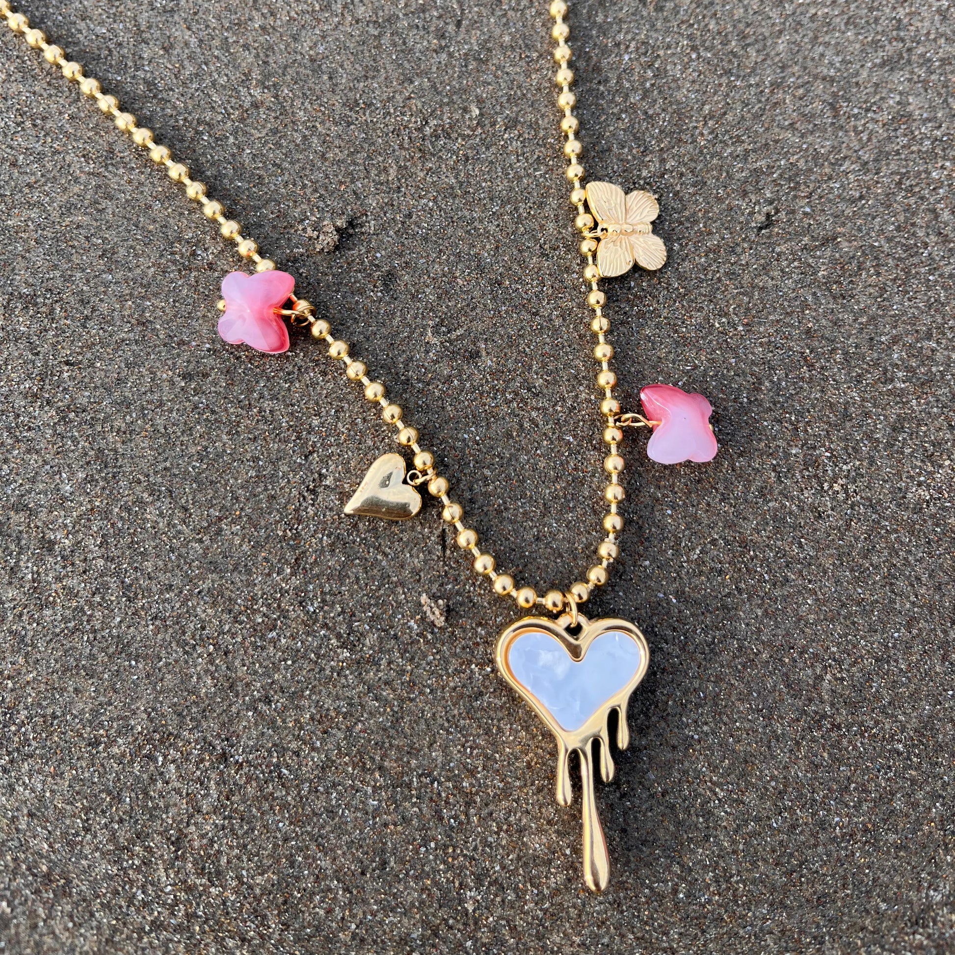 Necklace with heart-shaped pendant and floral charms on a textured surface