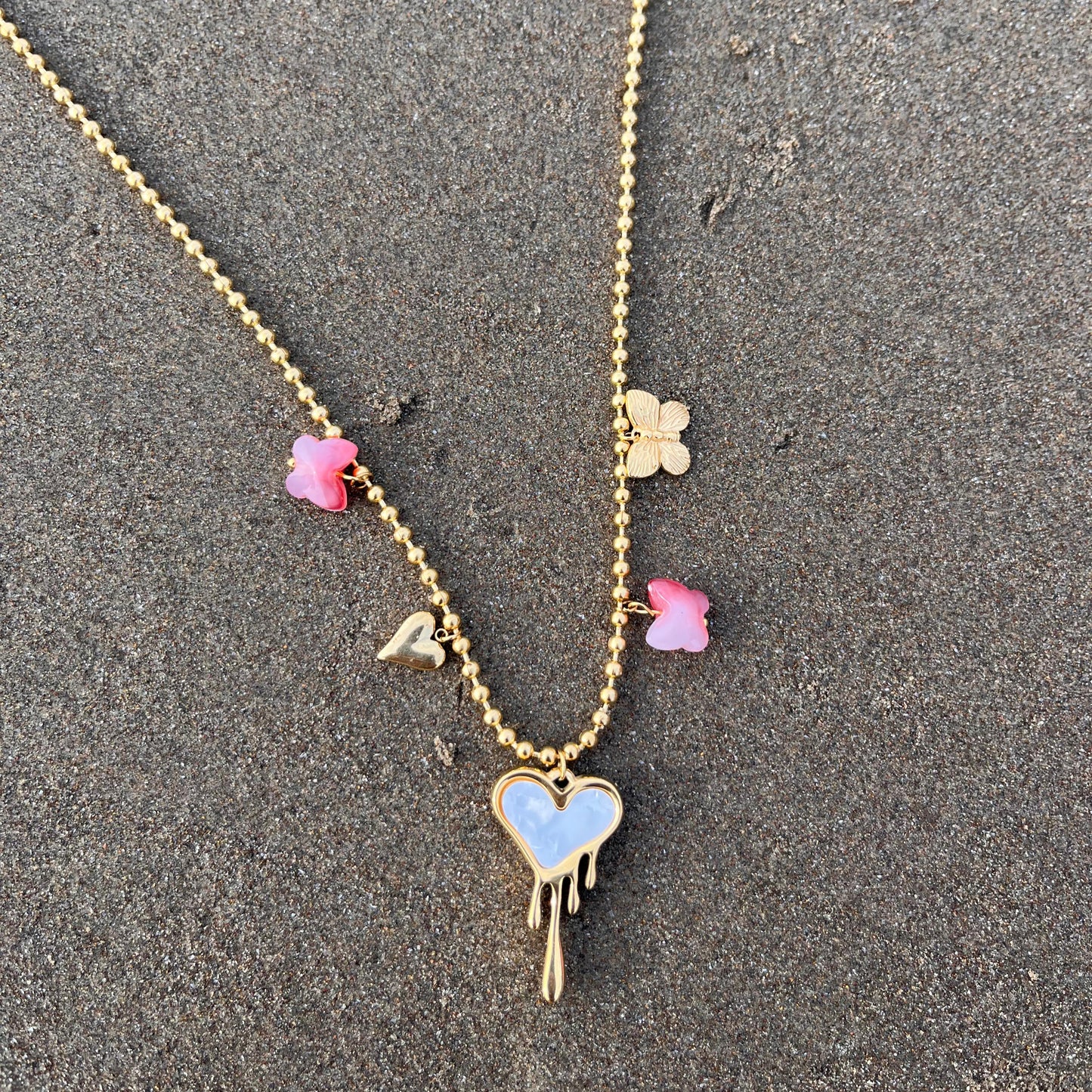 Necklace with heart and flower pendants on a textured surface