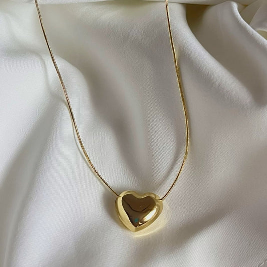 Gold heart-shaped necklace on a white fabric background
