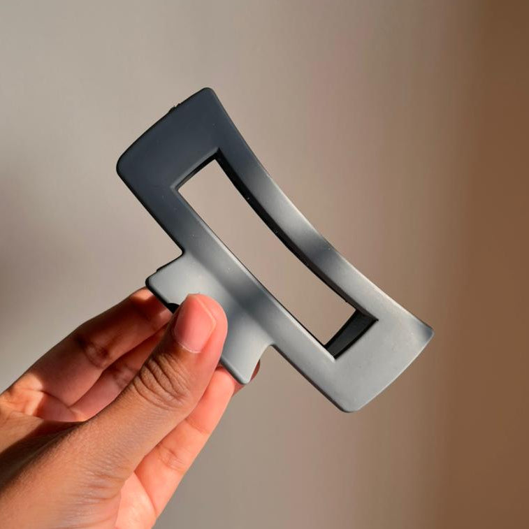 Hand holding a hair clip against a neutral background