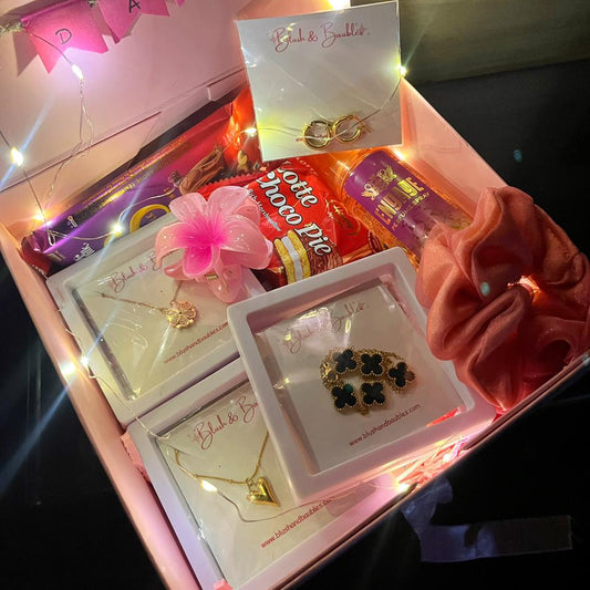 Gift box with jewelry and a card inside, decorated with lights.