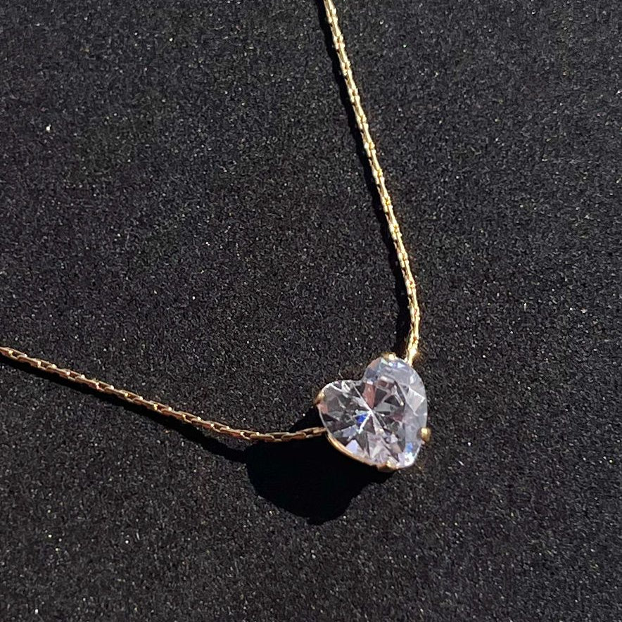 Necklace with a heart-shaped diamond pendant on a black background